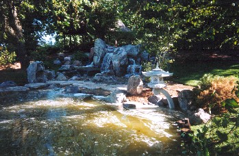 Pond near waterfall with a wonderful stone lantern. Osaka Garden
